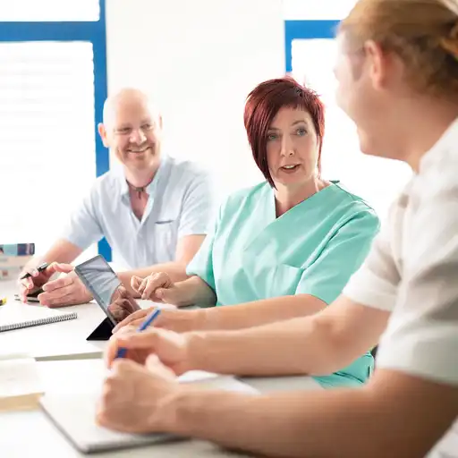 Eine Pflegerin im Gespräch mit zwei Personen